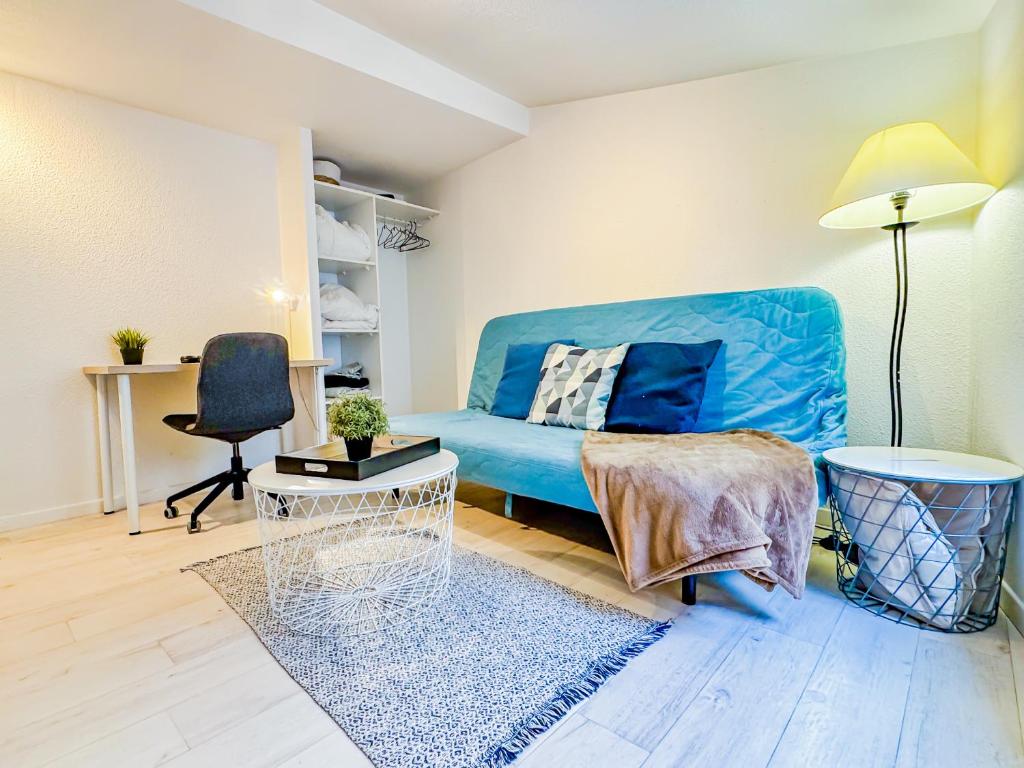 a living room with a blue couch and a chair at Studio cosy sous les toits en plein centre-ville in Clermont-Ferrand