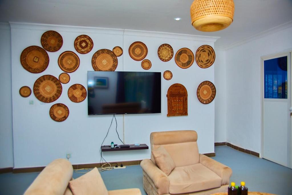 ザンジバルシティにあるMbweni Apartmentの椅子とテレビと木の皿が置かれたリビングルーム