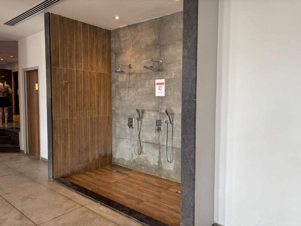 a shower in a bathroom with a wooden wall at Caesar Blue Resort Spa Sea view apartment H-49 in Vrysoules