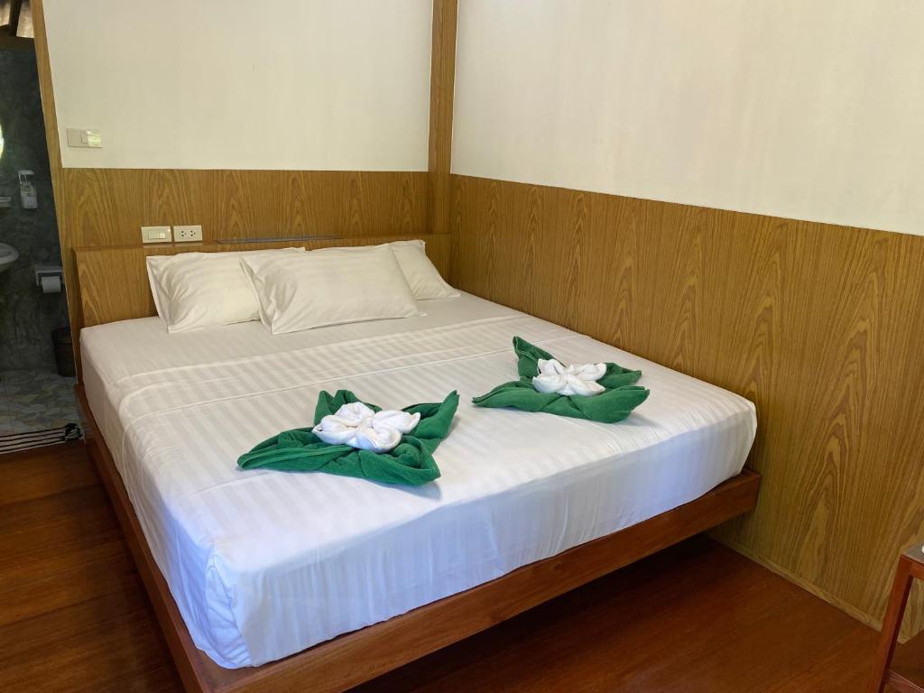 a bed with two white flowers on it at Mook Happy Bungalow in Koh Mook