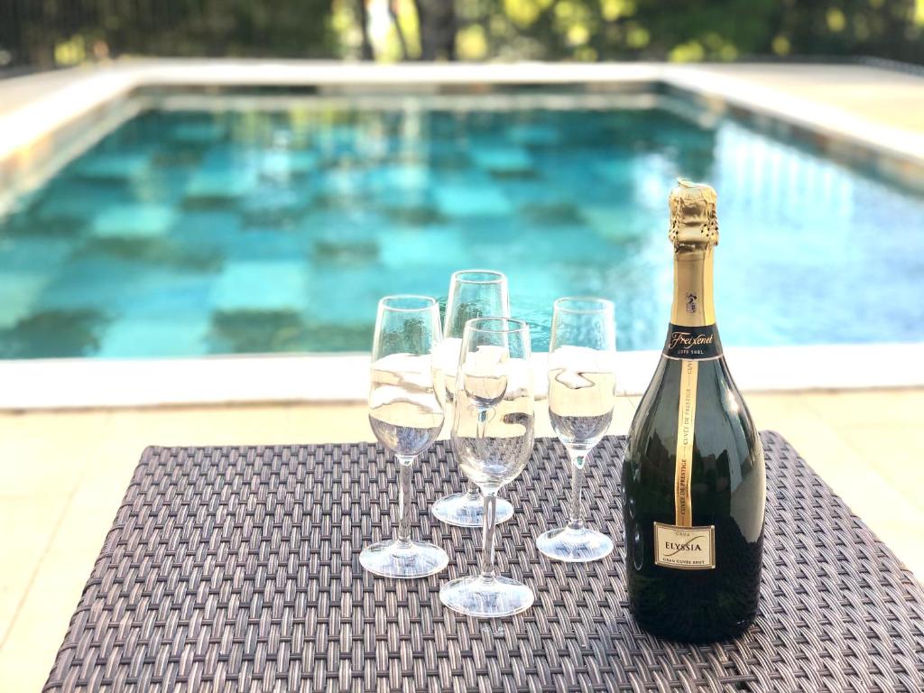 een fles wijn en glazen op een tafel naast een zwembad bij Global Immo 9101 Pacheco Beach in Roses