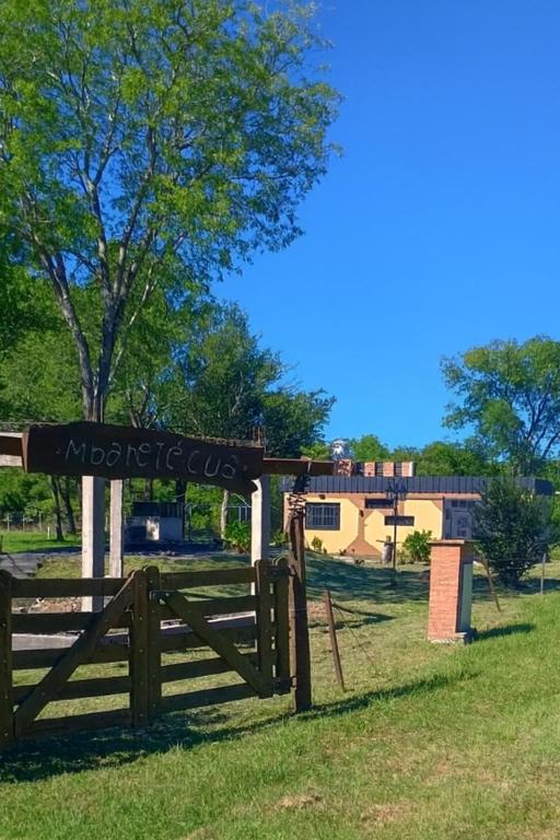 a wooden fence in a field with a building in the background at Cabaña Mbaretecua in Paso de la Patria