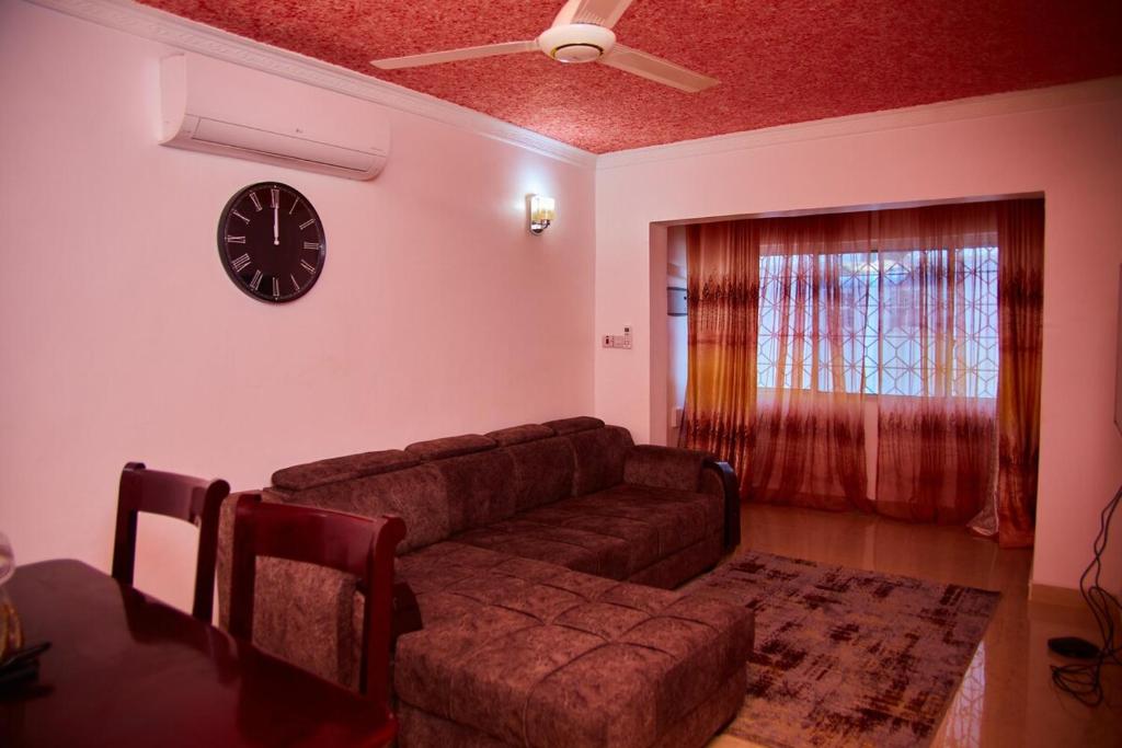 Una sala de estar con un sofá y un reloj en la pared. en Kilimani Apartment 1, en Migombani