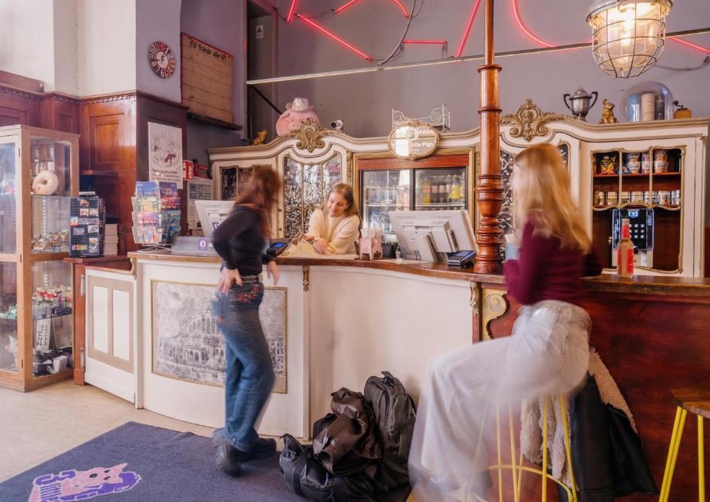 two women standing at the counter of a bar at Three Little Pigs Hostel - Your Berlin Castle in Berlin