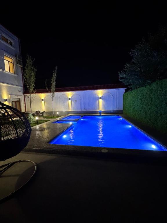 a swimming pool at night with blue lights at Turon City Hotel in Samarkand