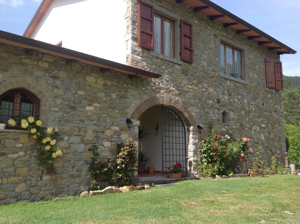 a stone house with a door and a yard at Agriturismo La Casa Bianca in Poppi