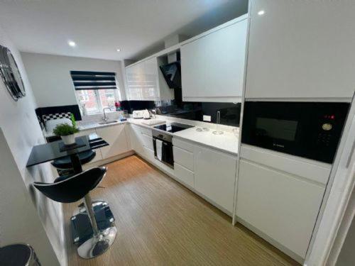 une cuisine avec des placards blancs et une chaise noire dans l'établissement Majestic, modern & spacious harbour-view apartment with parking, à Whitby