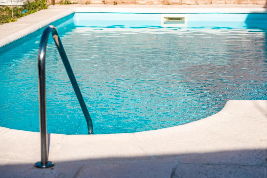 a swimming pool with a hand rail in the water at HOSTERIA NIDO DE CONDORES-Solo Adultos in Mina Clavero