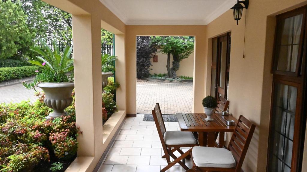 LUXURY ROOM @ 4 STAR GUEST HOUSE في ميدلبرغ: شرفة بها طاولة وكراسي وفناء