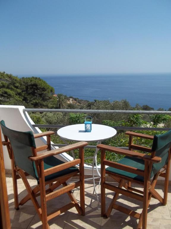 een tafel en 2 stoelen op een balkon met uitzicht op de oceaan bij Zacharoula Rooms in Manganítis