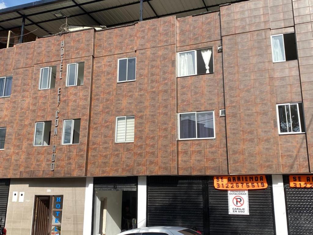 un edificio de ladrillo con ventanas y un coche aparcado delante en Hotel el CONDADO, en Itagüí