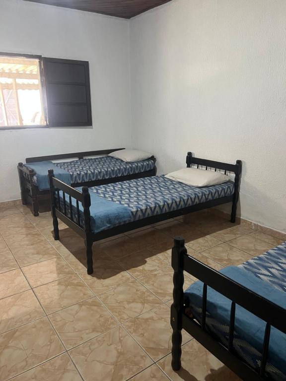 drie bedden in een kamer met een tv aan de muur bij Quarto privativo em casa de praia próxima a cachoeira in Bertioga