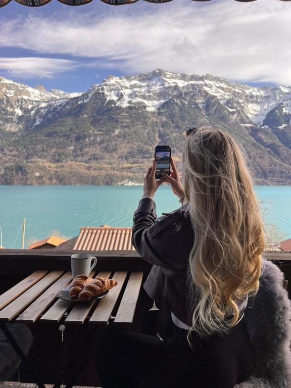 a woman taking a picture of a mountain with her cell phone at Breathtaking Lake & Mountain View Apartment 2 in Niederried