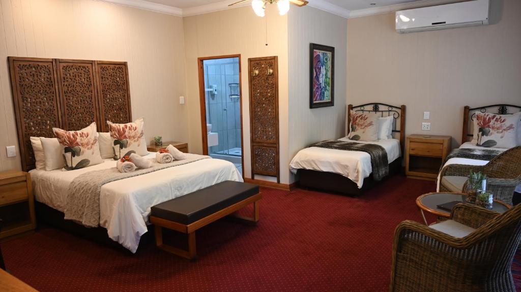 LUXURY FAMILY EN-SUITE ROOM @ 4 STAR GUEST HOUSE في ميدلبرغ: غرفة فندقية بسريرين وغرفة معيشة