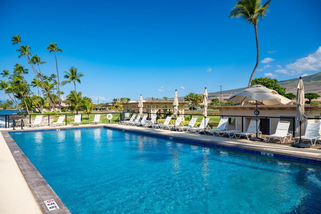 een groot zwembad met stoelen en palmbomen bij Puamana 240-3 in Lahaina