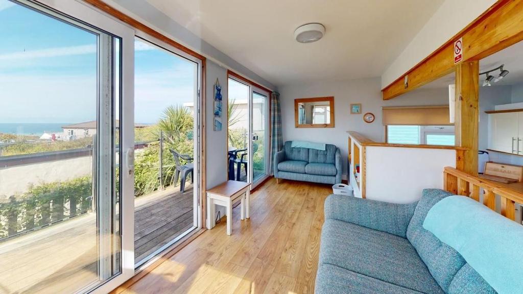 a living room with a couch and a balcony at C23 Wilmar, Riviere Towans in Hayle