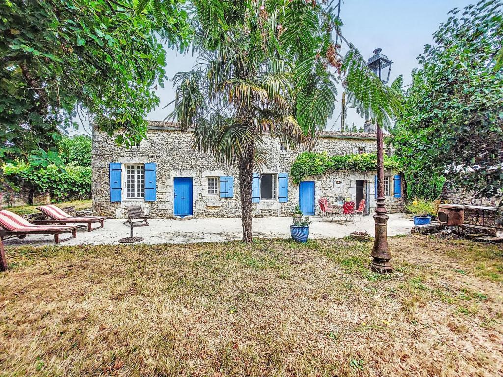 a stone house with blue doors and a palm tree at Holiday Home Les Vidalières by Interhome in Saint-Sulpice-dʼArnoult
