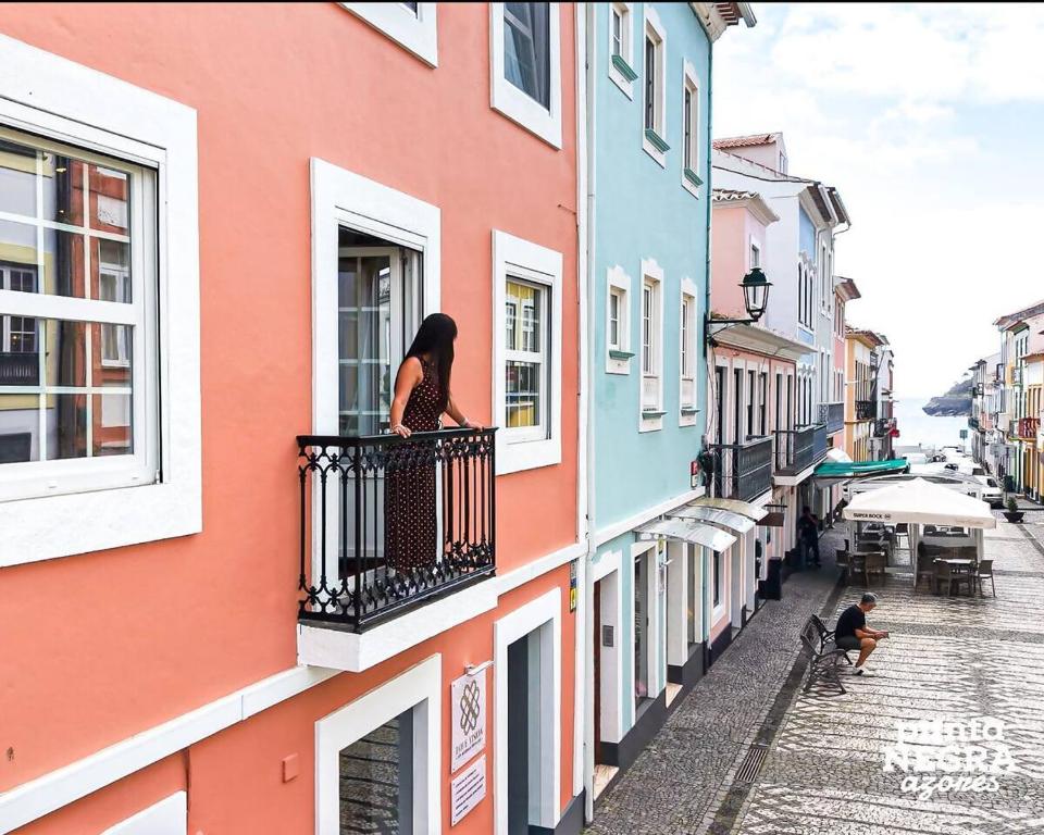 una donna su un balcone che guarda fuori da un edificio di Angra Soul 1 - By PontaNegraAzores ad Angra do Heroísmo