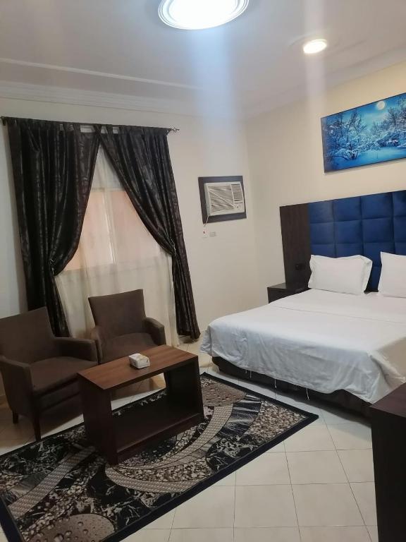 a bedroom with a bed and a chair and a table at فخامة المصيف للشقق المخدومة 2 in Taif