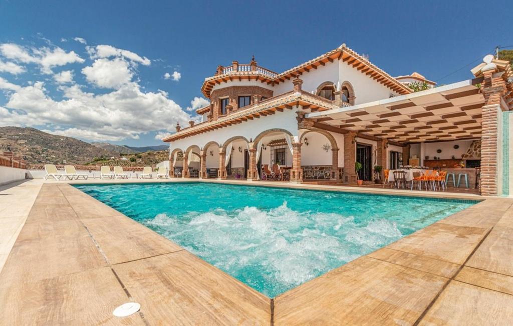 a villa with a swimming pool in front of a house at Villa el Cortijo in Torrox