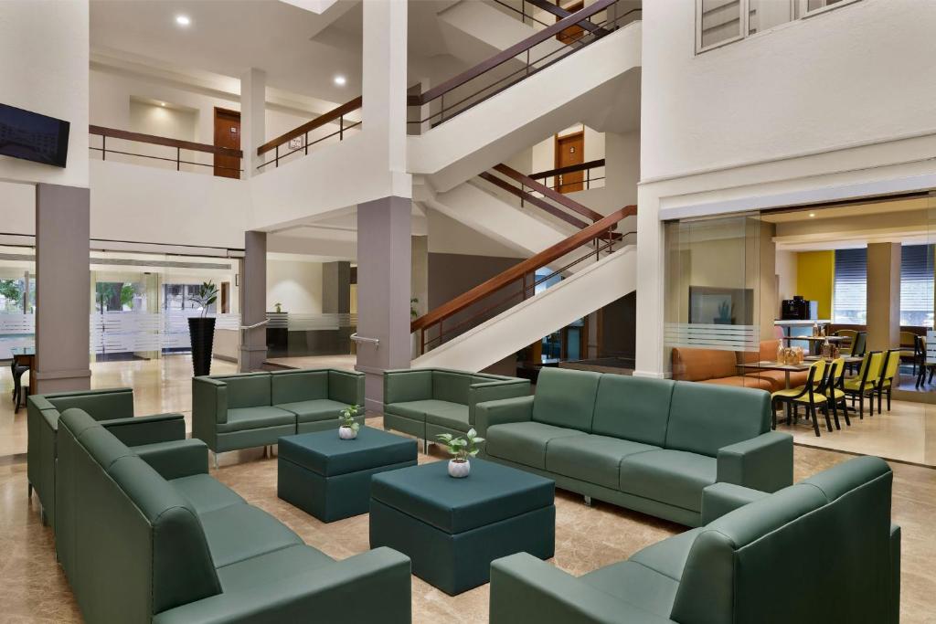 a lobby with green furniture and a staircase at The Fern Residency Woodland, Pune, Series by Marriott in Pune