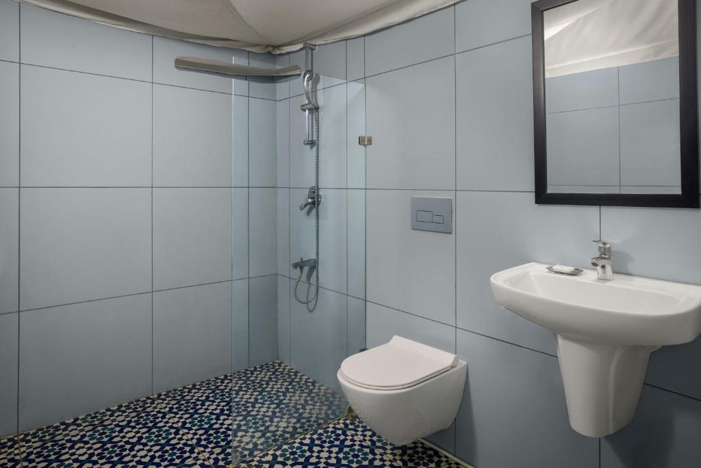 The Fern Seaside Luxurious Tent Resort Daman, Series by Marriott في دامان: حمام أبيض مع حوض ومرحاض