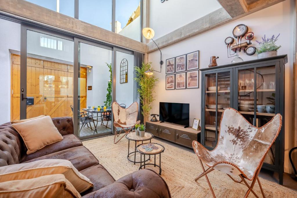 a living room with a couch and chairs and a tv at The Warehouse - Industrial Loft in Faro