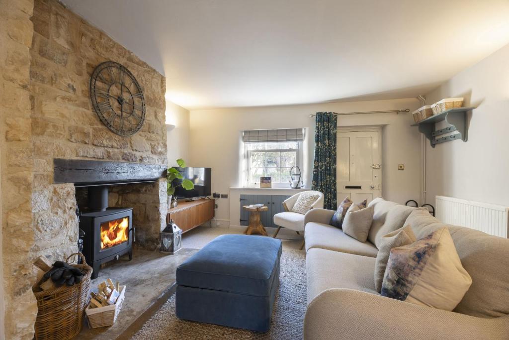 een woonkamer met een bank en een open haard bij Charming Cotswold Cottage in Central Winchcombe in Winchcombe