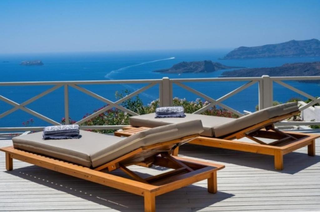 two beds on a deck with a view of the ocean at Santo Blue Santorini Caldera View Luxury Houses in Megalokhori