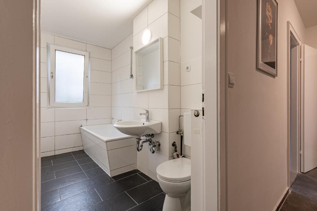 MK Apartments Delmenhorst nähe Bremen 1 في دلمنهورست: حمام أبيض مع حوض ومرحاض