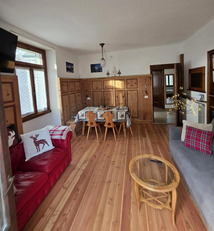 a living room with a red couch and a table at Appartamento 110mq Zona Terme posto auto privato in Bormio