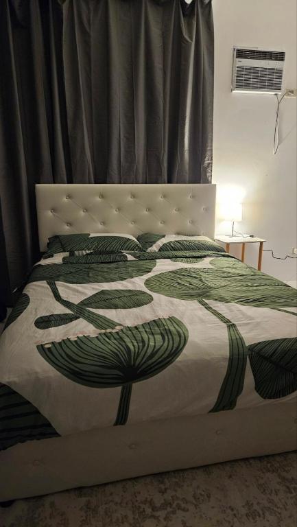 a bed with a green and white blanket on it at Edades Farms in Taysan