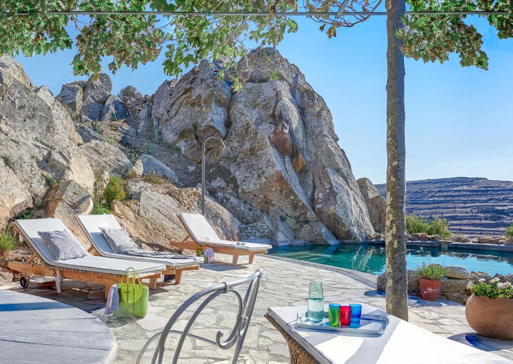 a swimming pool with chairs and a mountain at Xinara House in Tripótamos