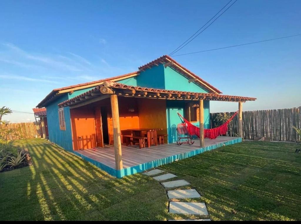 a small blue house with a porch and a hammock at Casa Beira rio Caraíva in Porto Seguro