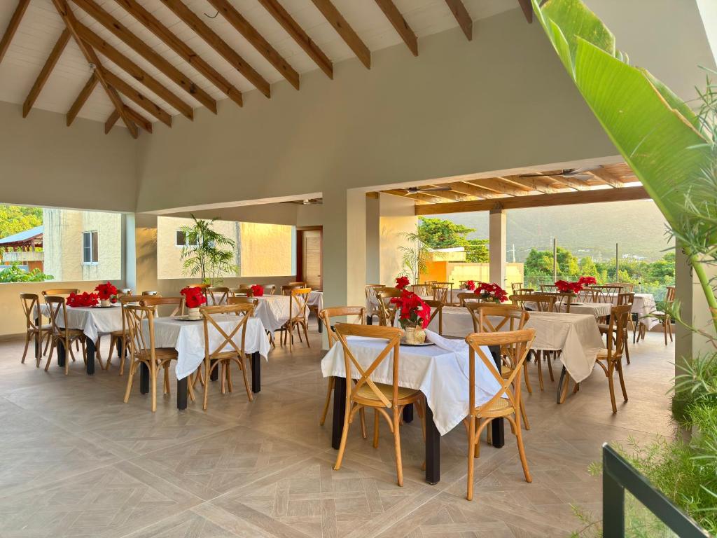 a restaurant with tables and chairs with red flowers on them at Ocean Winds Hotel Costambar Puerto Plata in San Felipe de Puerto Plata