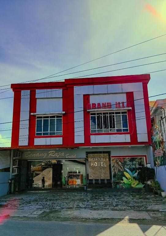 a red and white building with a sign on it at Hotel Grand illa palopo in Palopo