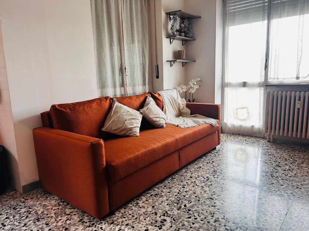 an orange couch in a living room with a window at Traiano 49 in Turin