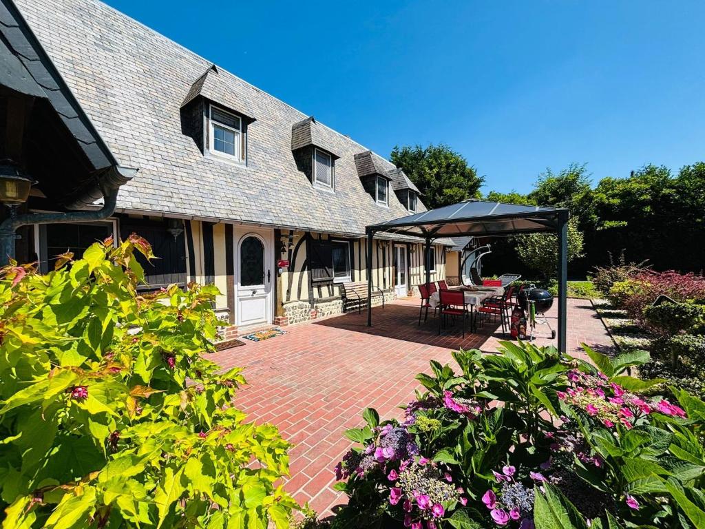 ein Haus mit einer Backsteinterrasse mit Tischen und Stühlen in der Unterkunft Chambres d'hôtes accès au spa in Lieurey