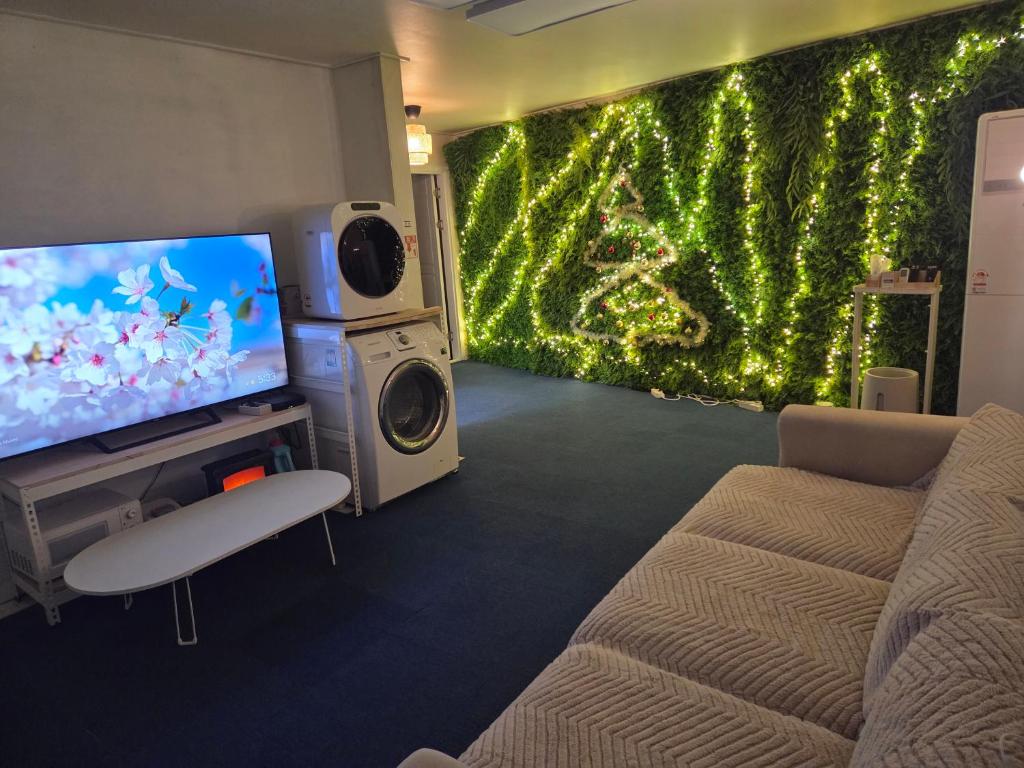 a living room with a large screen tv and a couch at Moomoo House in Busan