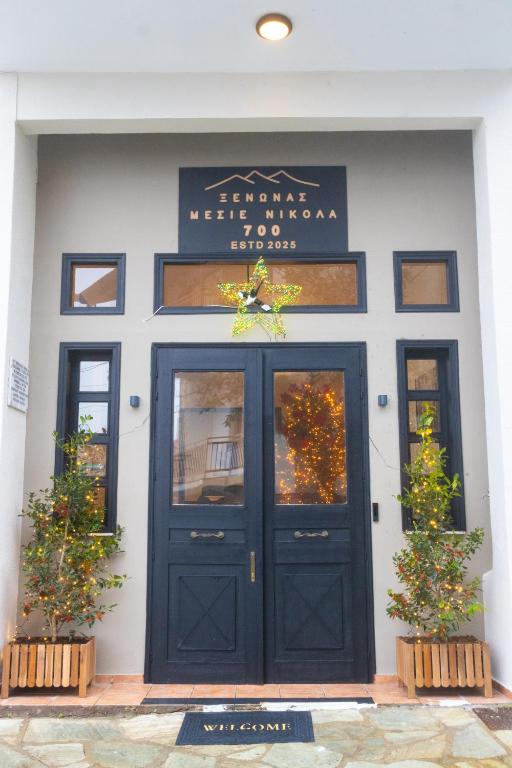 a black door on a white building with two plants at Μεσιέ Νικολά 700 in Mesenikólas