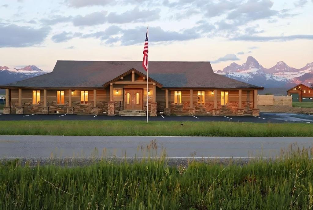 Una cabaña de troncos con una bandera estadounidense frente a las montañas. en Teton Crest Lodge Sleeps 24 Ideal Reunion Spot, en Driggs