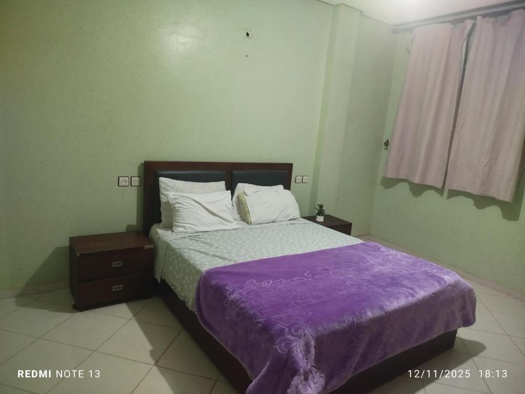 a bedroom with a bed with a purple blanket at App luxe riad zitoune in Meknès