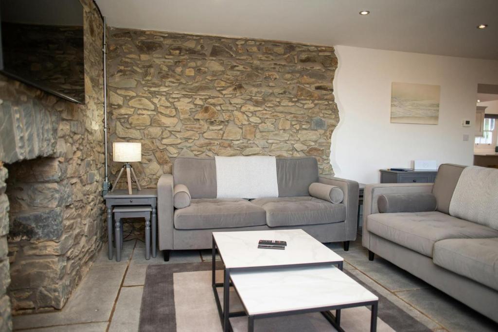 een woonkamer met 2 banken en een stenen muur bij Gelli Genlas Aberaeron in Synod