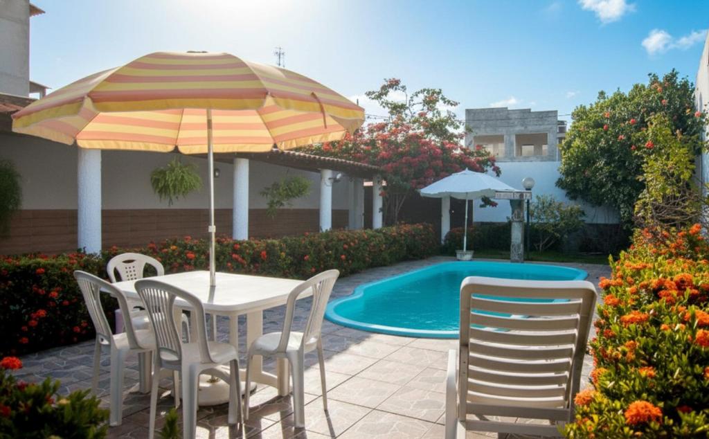 uma mesa e cadeiras com um guarda-sol e uma piscina em Casa com Piscina e Churrasqueira em Baixio em Baixio