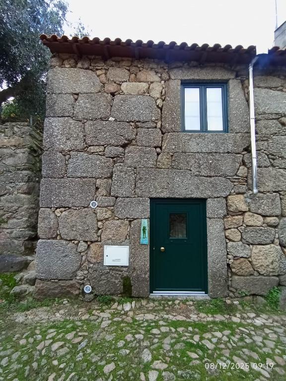a stone building with a green door and a window at Casa de Aldeia Vale do Mondego in Guarda