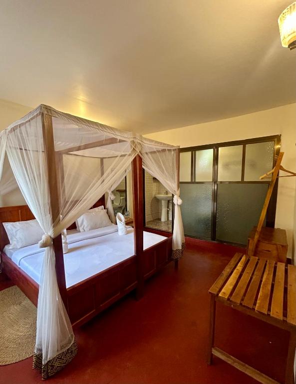 a bedroom with a canopy bed and a bench at Patamu Restaurants Lodge & Safaris in Karatu