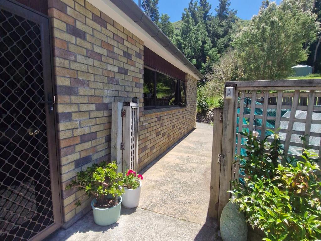 a wooden gate with two potted plants next to a building at Mikimiki Valley Cottage near Tararua Park Trailhead in Masterton