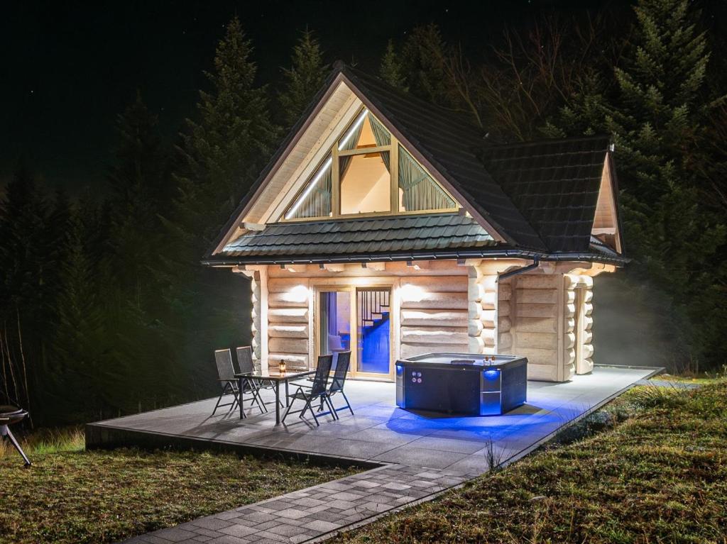 Zielone Wzgórze Sidzina في Sidzina: كوخ خشبي مع طاولة وكراسي وشواية