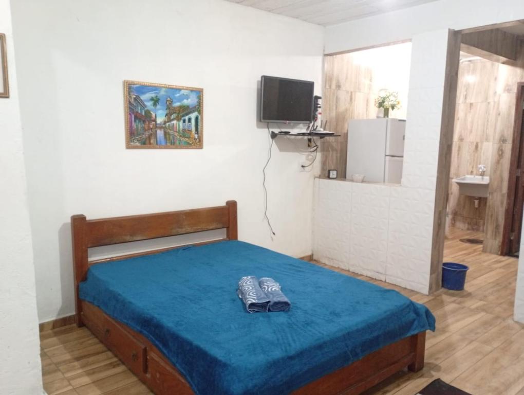 een slaapkamer met een bed met blauwe lakens en een televisie bij Cantinho da Serra da Bocaina - Chalé Casal in Paraty