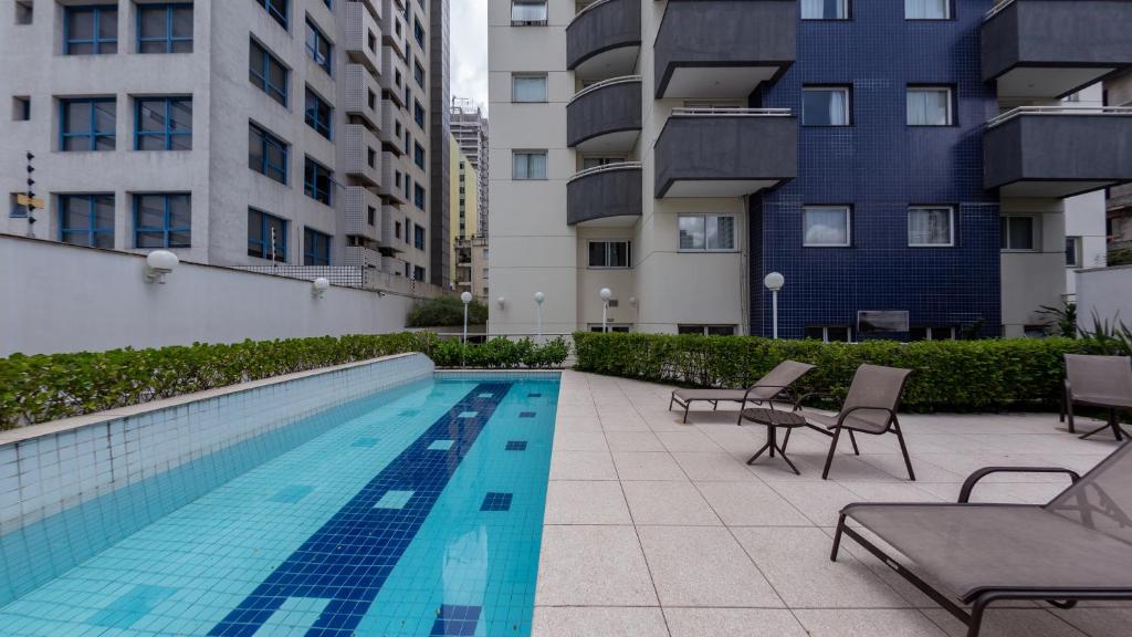 a swimming pool with chairs next to some buildings at St Charbel by Charlie in São Paulo
